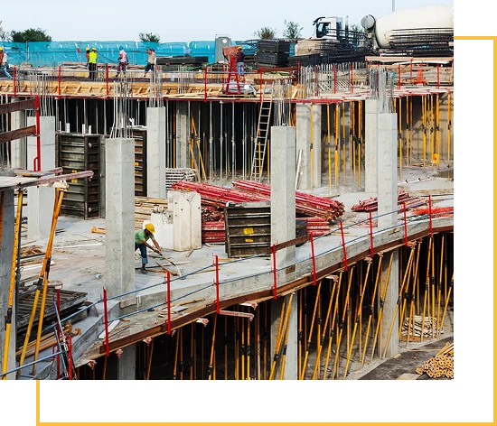 A construction site with workers, concrete columns, scaffolding, and building materials; yellow support beams and red railings are visible on different levels of the unfinished structure.